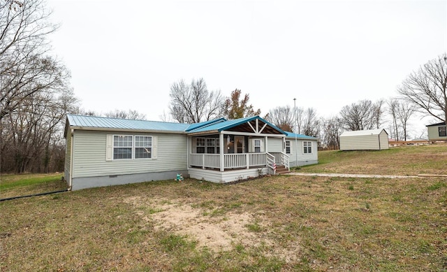 back of property featuring covered porch, a shed, and a lawn