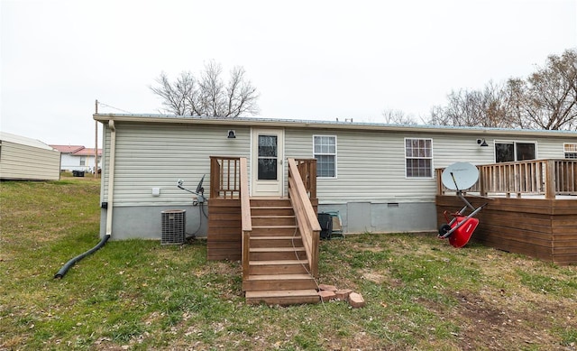 rear view of property featuring a lawn, central air condition unit, and a wooden deck