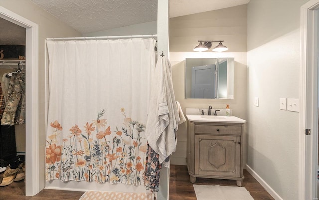 bathroom featuring vanity, wood-type flooring, lofted ceiling, and a textured ceiling