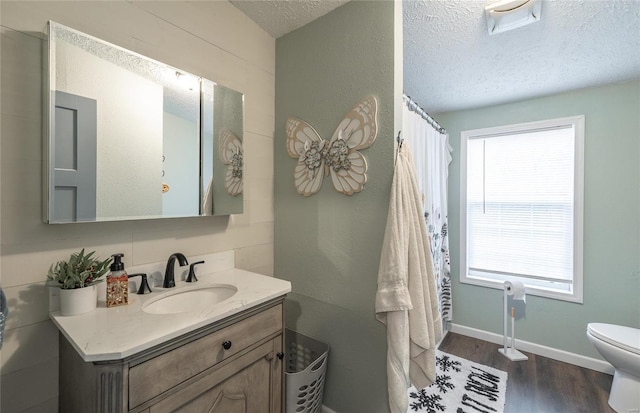 bathroom featuring hardwood / wood-style flooring, vanity, toilet, and a textured ceiling