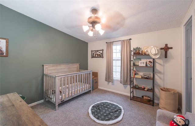 bedroom featuring ceiling fan, carpet floors, a textured ceiling, and a nursery area