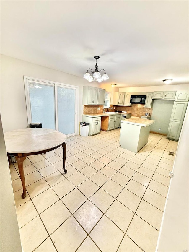 kitchen with sink, a notable chandelier, backsplash, pendant lighting, and a kitchen island