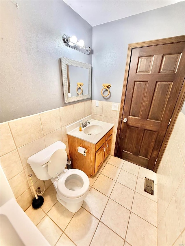 bathroom with tile patterned floors, vanity, tile walls, and toilet