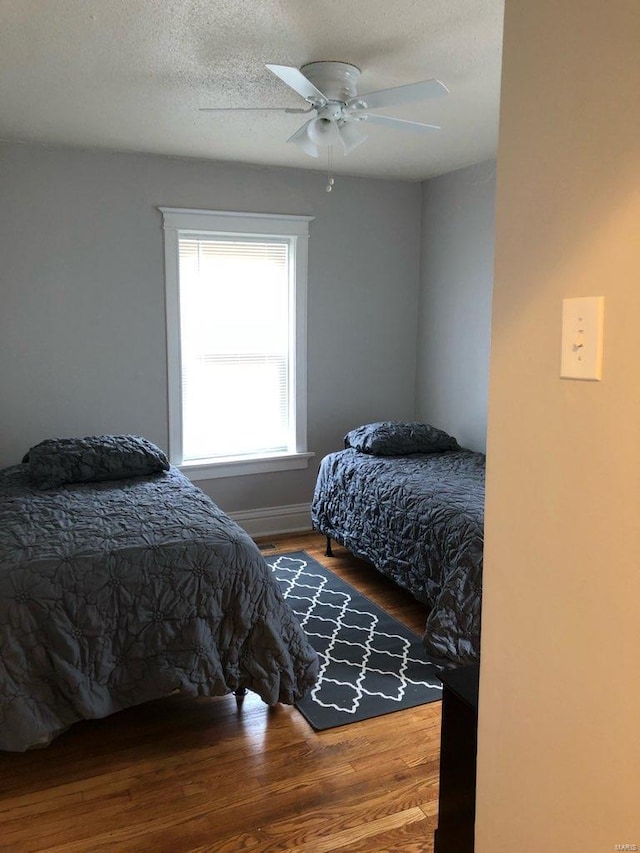 bedroom featuring ceiling fan, wood-type flooring, and a textured ceiling