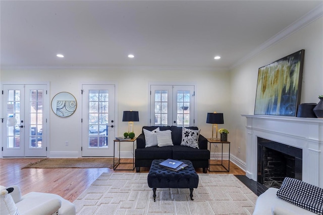 living room featuring light hardwood / wood-style floors, ornamental molding, and french doors