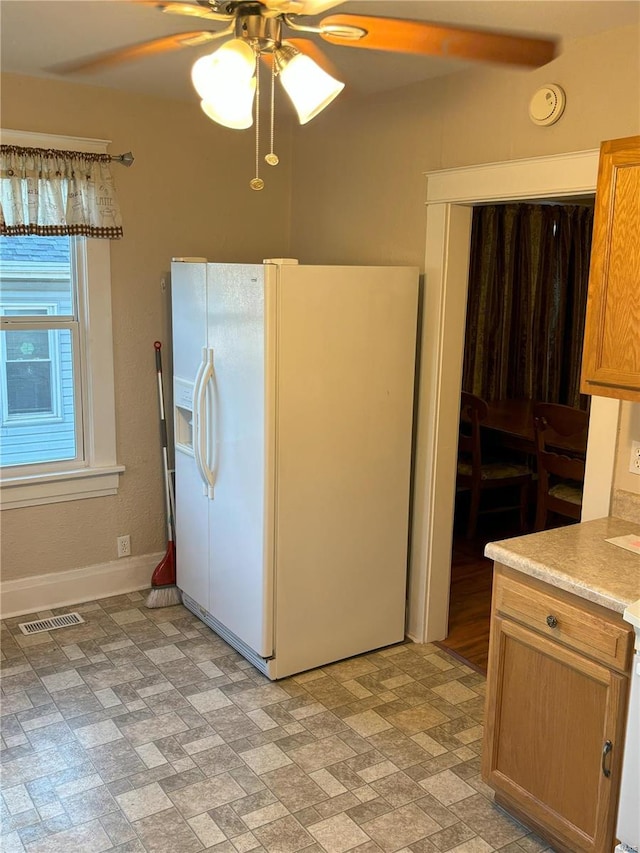 kitchen featuring ceiling fan and white refrigerator with ice dispenser