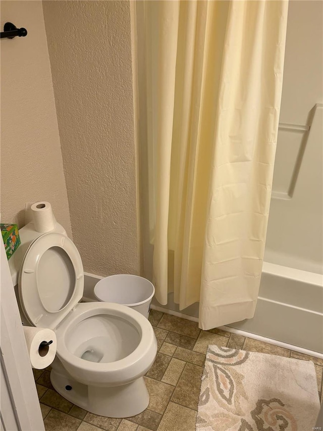 bathroom with toilet and shower / bath combo with shower curtain