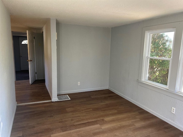 unfurnished room with dark hardwood / wood-style flooring and a textured ceiling