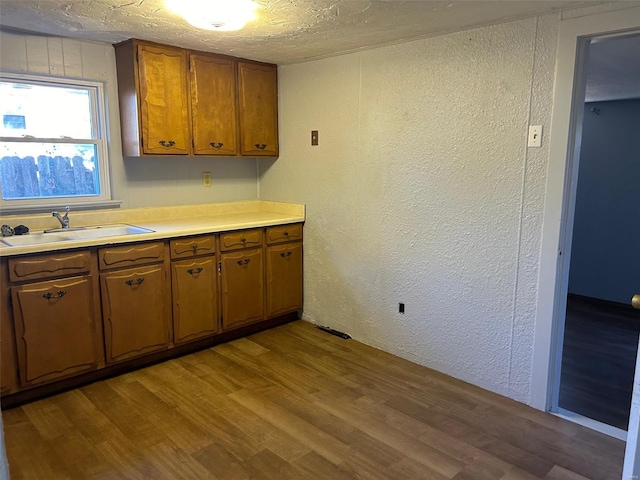 kitchen featuring light hardwood / wood-style flooring, a textured ceiling, and sink