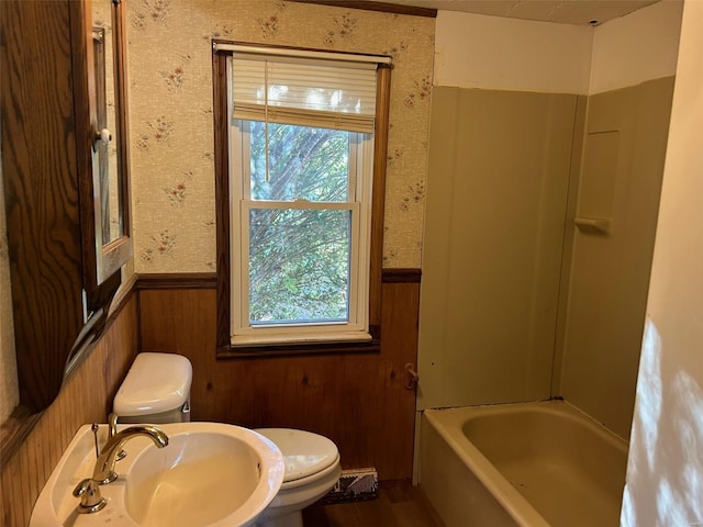 bathroom featuring toilet, sink, and wooden walls