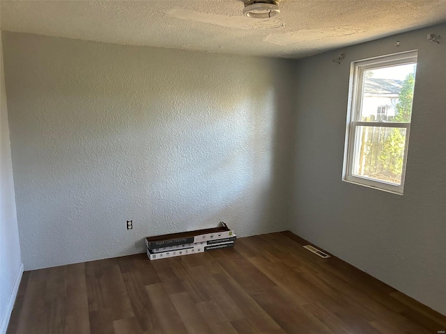 unfurnished room featuring dark hardwood / wood-style flooring and a textured ceiling