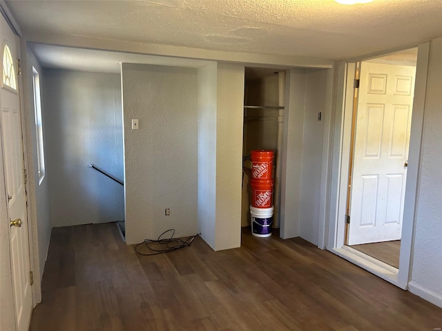 unfurnished bedroom with a textured ceiling, dark wood-type flooring, and a closet