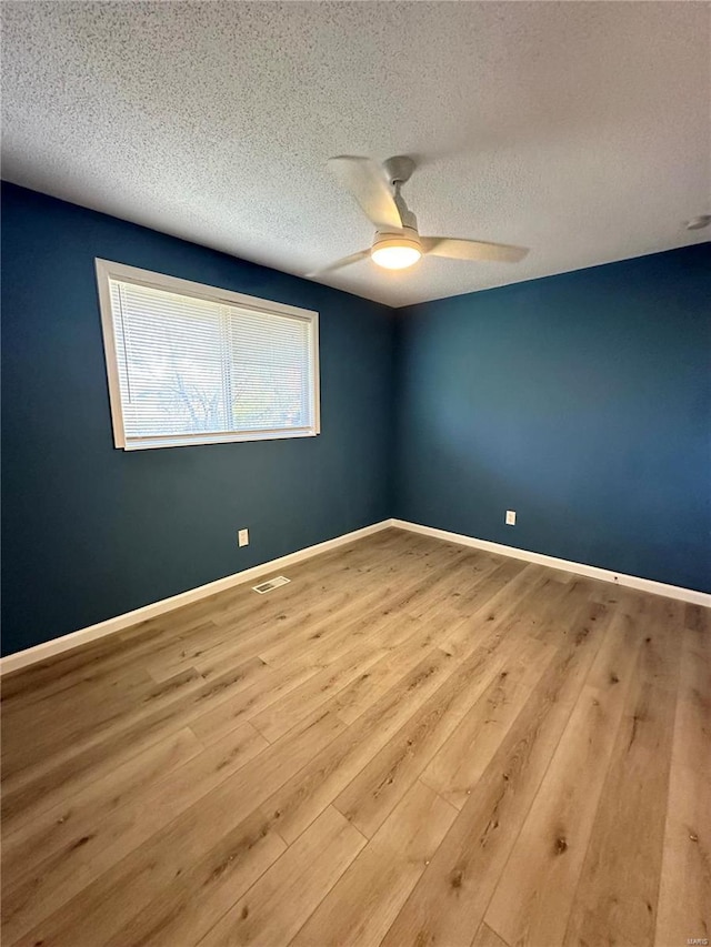 spare room featuring a textured ceiling, light wood-type flooring, and ceiling fan