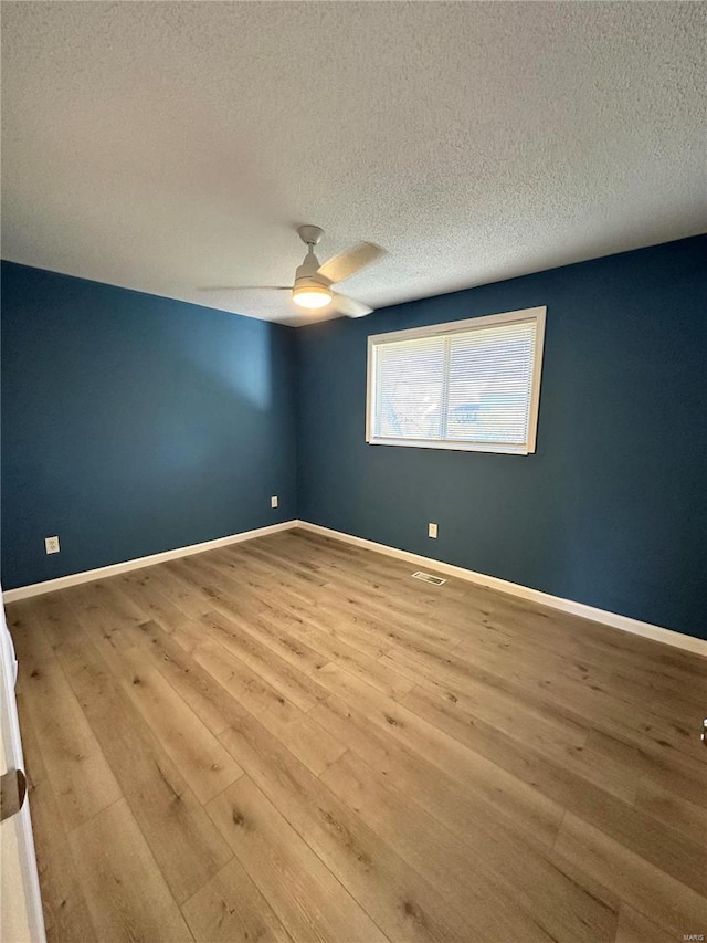 spare room with ceiling fan, light wood-type flooring, and a textured ceiling