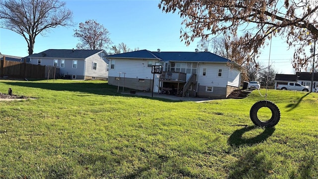 back of property with a wooden deck and a lawn