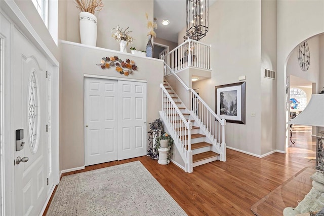 entryway with hardwood / wood-style flooring, a towering ceiling, and a chandelier