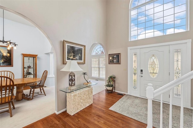 entrance foyer with decorative columns, hardwood / wood-style floors, and a high ceiling