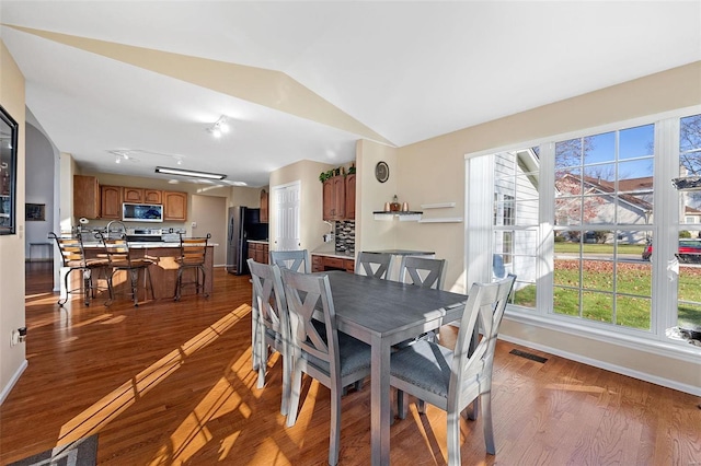 dining space featuring plenty of natural light, wood-type flooring, and lofted ceiling