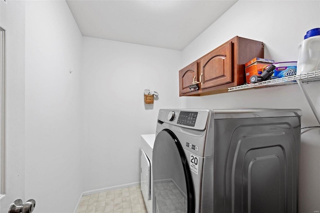 clothes washing area with cabinets and washing machine and clothes dryer