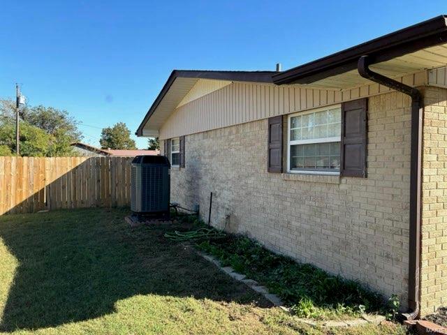 view of side of property featuring a lawn and central air condition unit