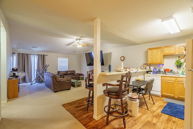 kitchen featuring light wood-type flooring, a breakfast bar, white appliances, vaulted ceiling, and ceiling fan