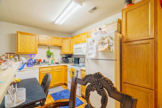 kitchen featuring a textured ceiling, white appliances, sink, light brown cabinets, and light hardwood / wood-style flooring