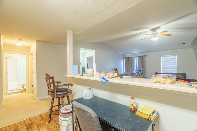 kitchen featuring hardwood / wood-style floors, lofted ceiling, ceiling fan, a textured ceiling, and a breakfast bar area