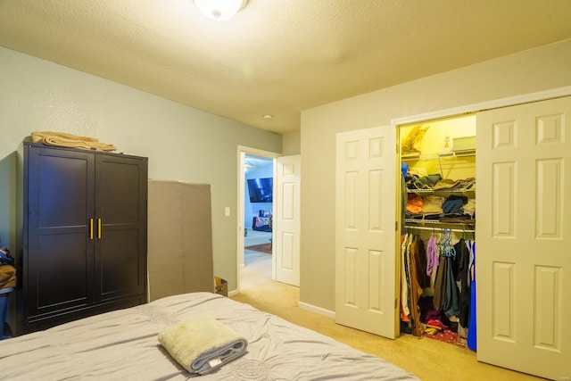 bedroom featuring a textured ceiling, a walk in closet, light carpet, and a closet