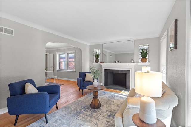 living room with hardwood / wood-style floors, a brick fireplace, and crown molding