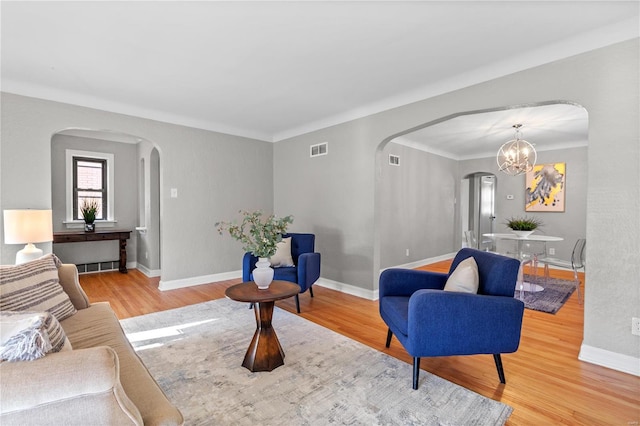 living room featuring hardwood / wood-style floors, ornamental molding, and an inviting chandelier