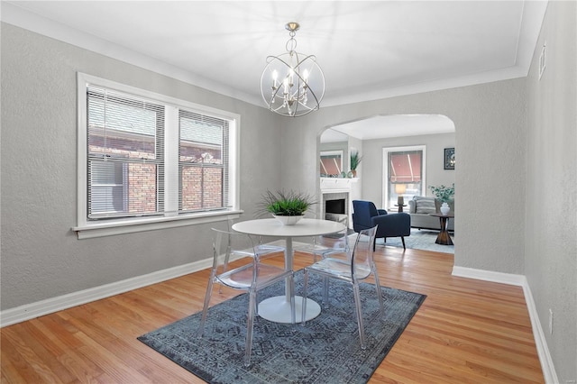 dining space with a fireplace, hardwood / wood-style floors, plenty of natural light, and crown molding