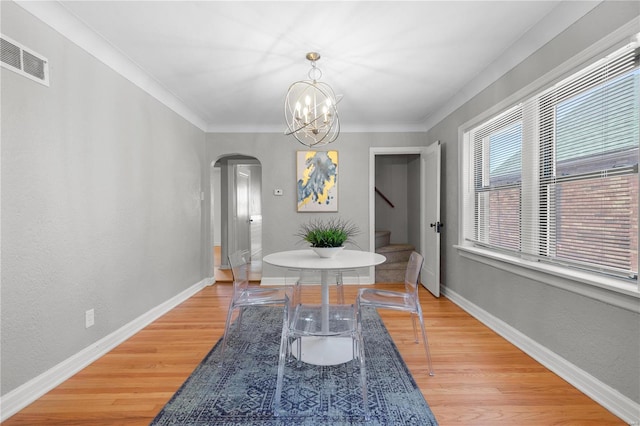 dining space featuring an inviting chandelier, light hardwood / wood-style flooring, and ornamental molding