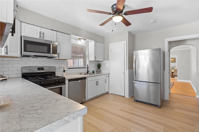 kitchen featuring decorative backsplash, light hardwood / wood-style flooring, white cabinets, and stainless steel appliances