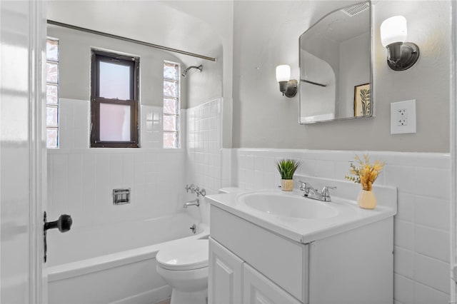 full bathroom featuring toilet, vanity, tile walls, and tiled shower / bath