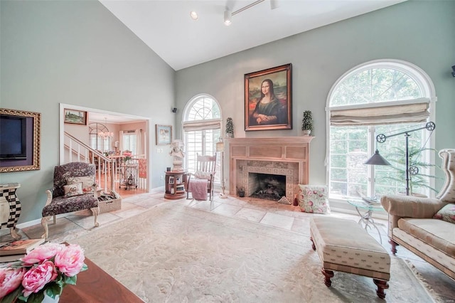 living room featuring a notable chandelier, high vaulted ceiling, and a premium fireplace