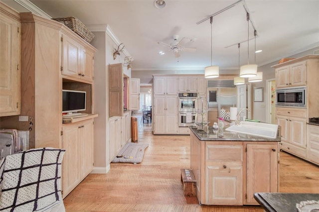 kitchen with hanging light fixtures, ornamental molding, built in appliances, a center island with sink, and light hardwood / wood-style flooring