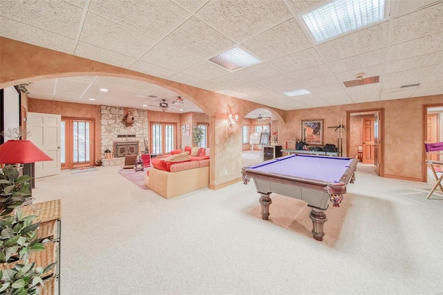 playroom featuring light carpet, a stone fireplace, and a drop ceiling