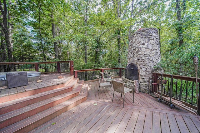 wooden terrace with a jacuzzi, an outdoor stone fireplace, and outdoor dining area