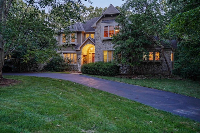 view of front of property with stone siding, aphalt driveway, and a front yard