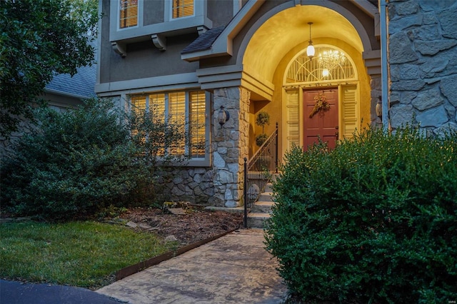 view of exterior entry featuring stone siding and stucco siding