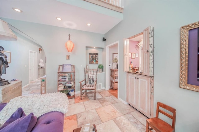 interior space with baseboards, arched walkways, stone tile floors, and recessed lighting