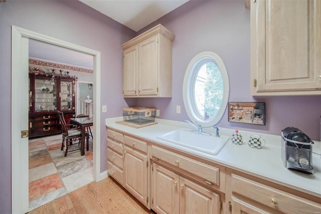 kitchen featuring light countertops, light brown cabinetry, and a sink