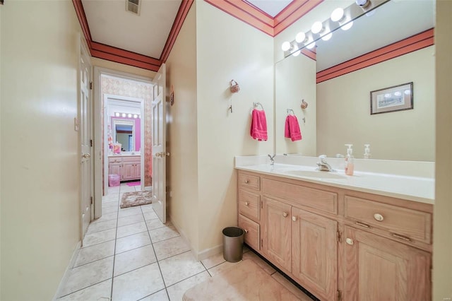 bathroom featuring vanity, baseboards, visible vents, tile patterned floors, and crown molding