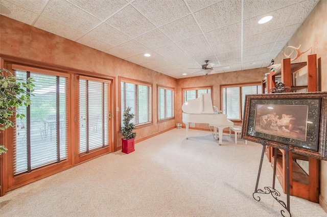 living area featuring carpet floors, baseboards, a drop ceiling, and recessed lighting