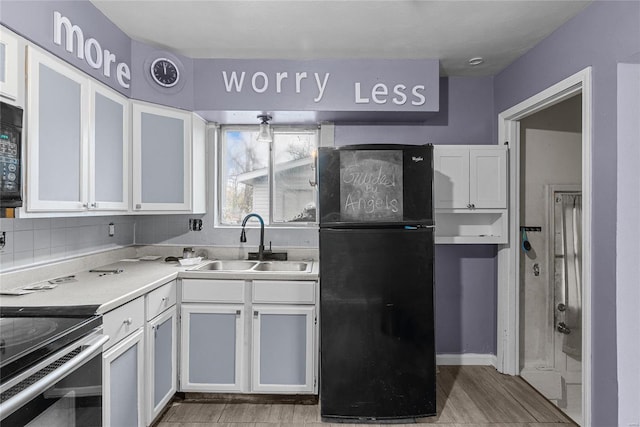 kitchen with sink, backsplash, white cabinetry, and black appliances