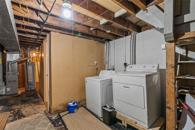 clothes washing area featuring washer and clothes dryer, gas water heater, and heating unit