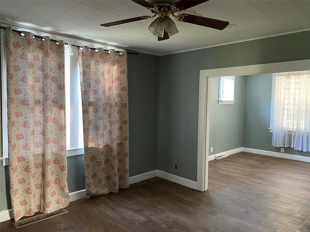 empty room with ceiling fan, ornamental molding, and dark wood-type flooring