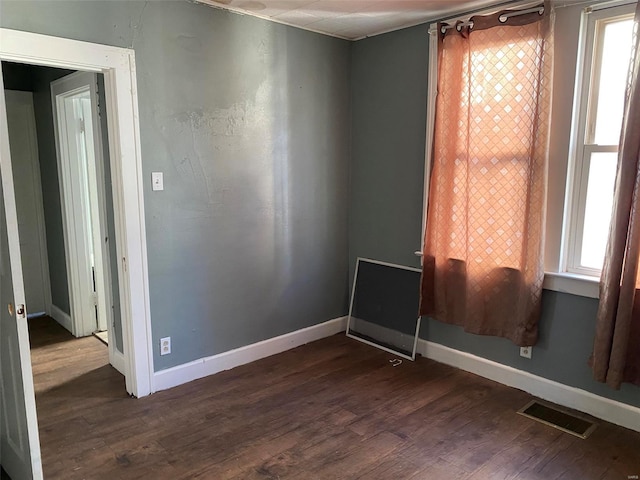 empty room with dark hardwood / wood-style flooring and plenty of natural light