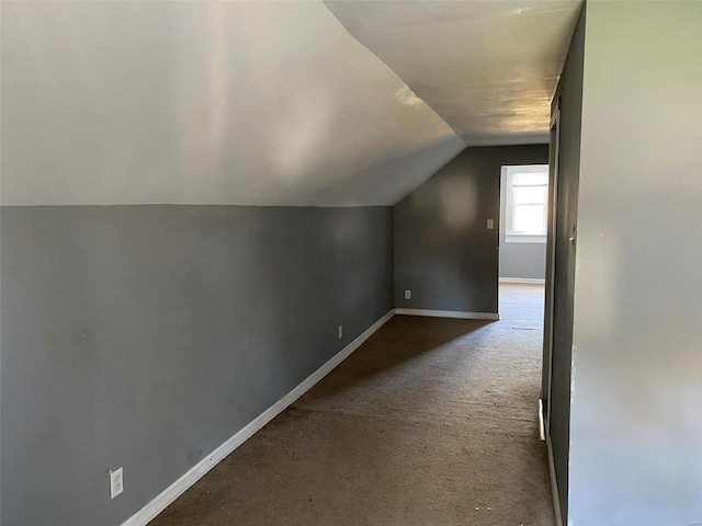 additional living space featuring dark colored carpet and vaulted ceiling