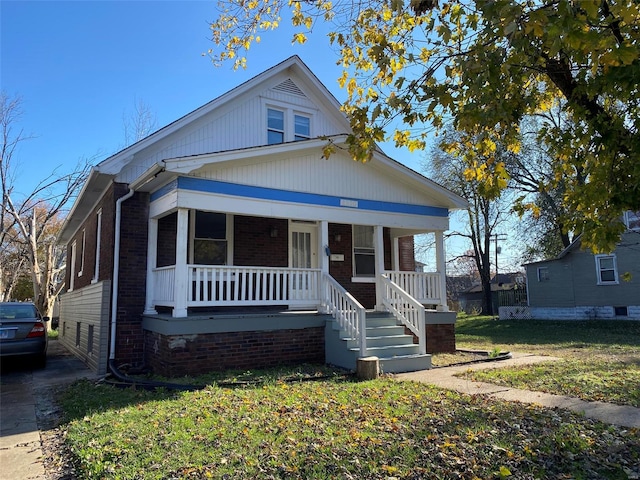 bungalow-style house featuring covered porch and a front yard